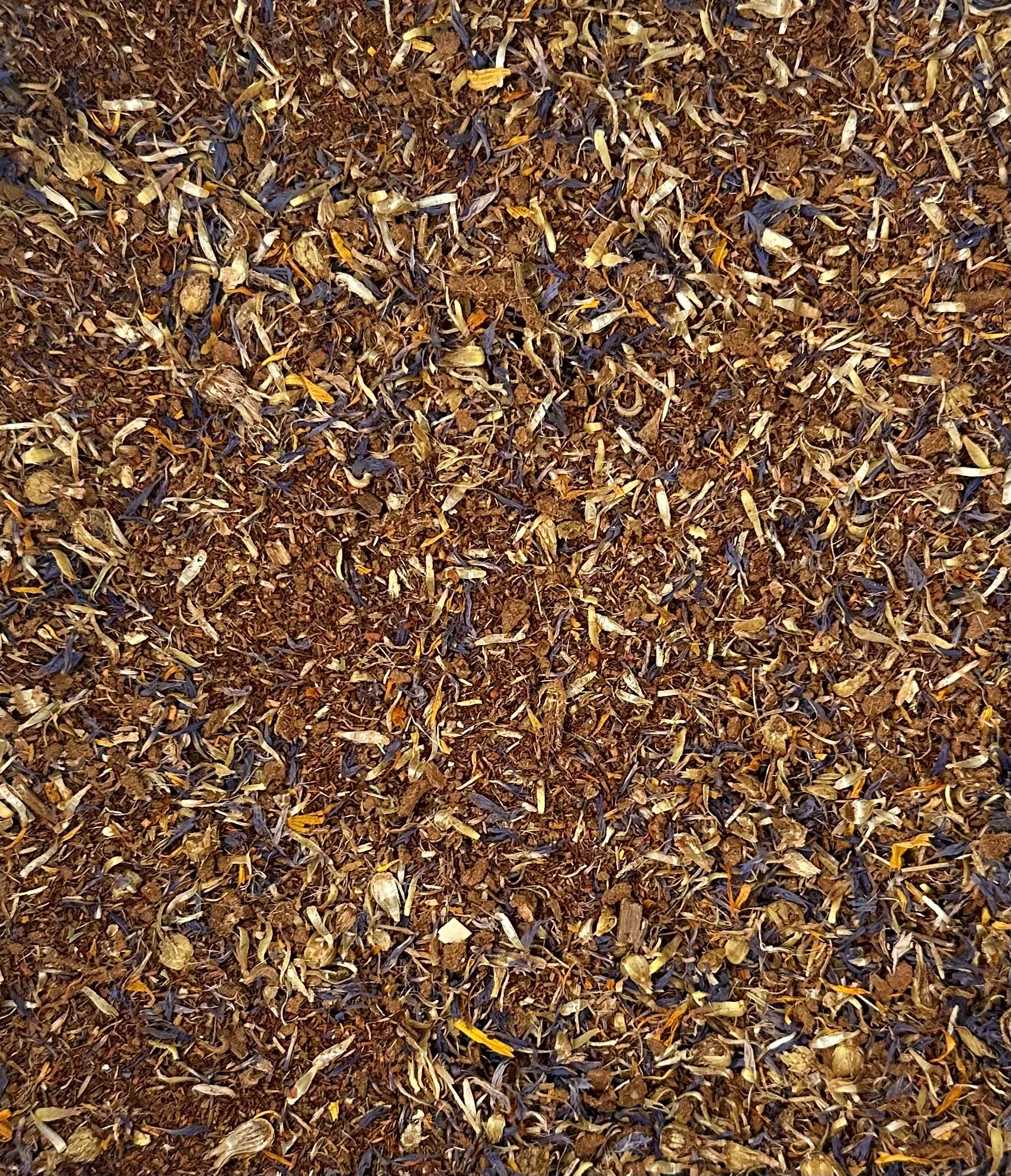 Close-up of dried herbs and flowers in brown, yellow, and purple, resembling organic teas.