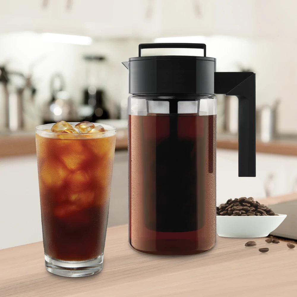 Two black tea infusers with mesh screens, one upright and one inverted, beside piles of coffee grounds and loose organic teas.